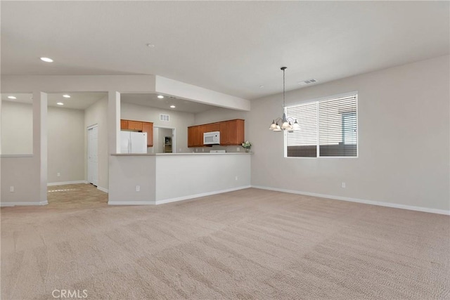 unfurnished living room featuring an inviting chandelier and light colored carpet