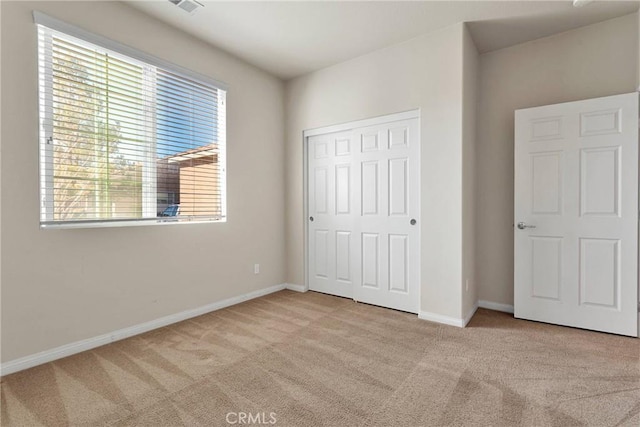 unfurnished bedroom featuring a closet and light carpet