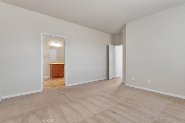 unfurnished bedroom featuring connected bathroom, sink, and light carpet