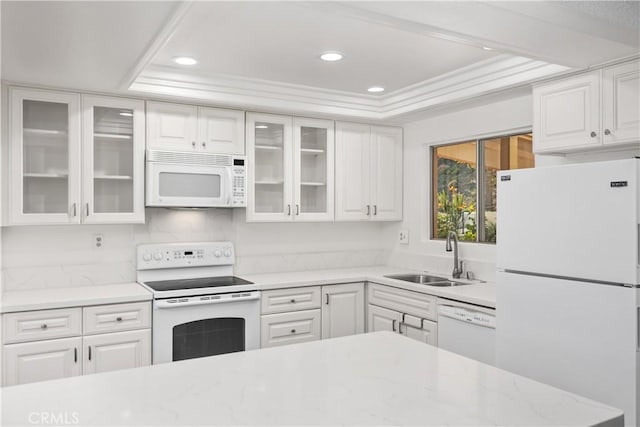 kitchen with a tray ceiling, sink, white appliances, and white cabinets