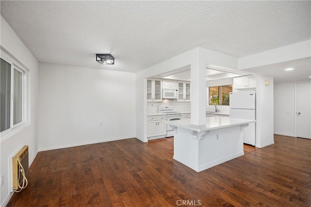 kitchen featuring a kitchen island, sink, white cabinets, a kitchen breakfast bar, and white appliances