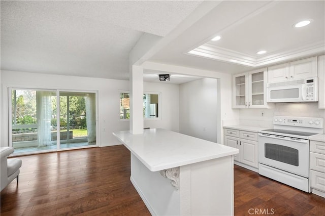 kitchen featuring a kitchen island, white cabinetry, dark hardwood / wood-style flooring, a kitchen bar, and white appliances