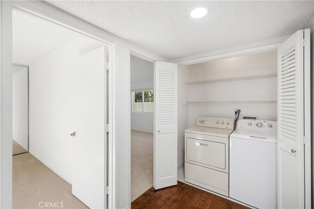 laundry room with dark hardwood / wood-style flooring, a textured ceiling, and washer and clothes dryer