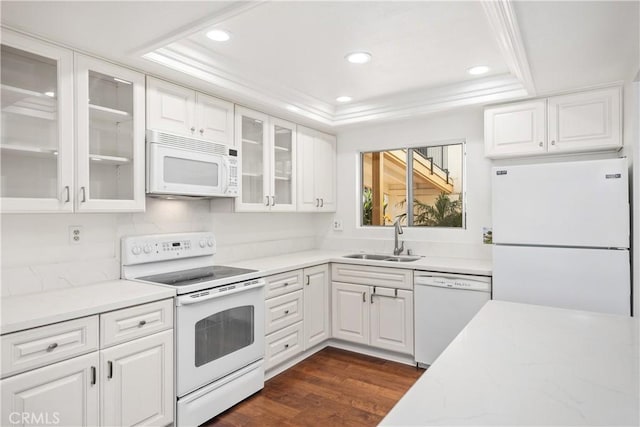 kitchen with a raised ceiling, white cabinetry, sink, and white appliances