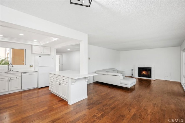 unfurnished living room with sink, dark wood-type flooring, a fireplace, and a textured ceiling