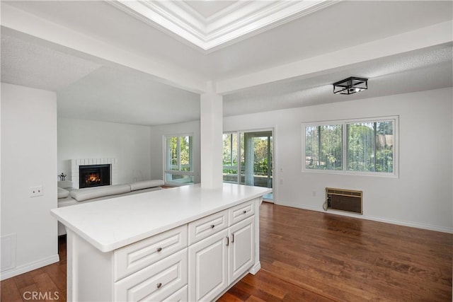 kitchen featuring white cabinetry, dark hardwood / wood-style floors, heating unit, a kitchen island, and a brick fireplace