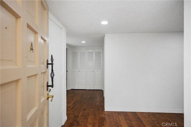 hallway featuring dark hardwood / wood-style floors and a textured ceiling