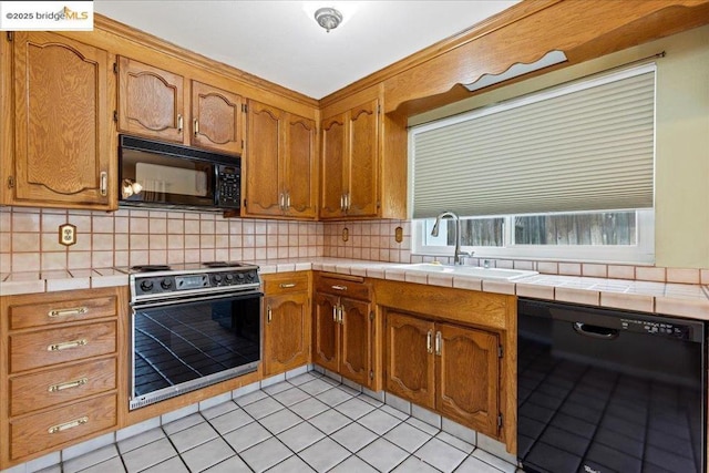 kitchen featuring tasteful backsplash, tile counters, sink, and black appliances