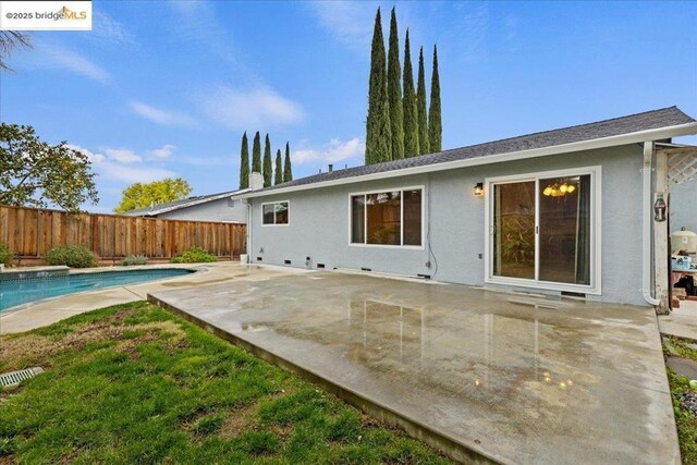 rear view of house featuring a fenced in pool and a patio area