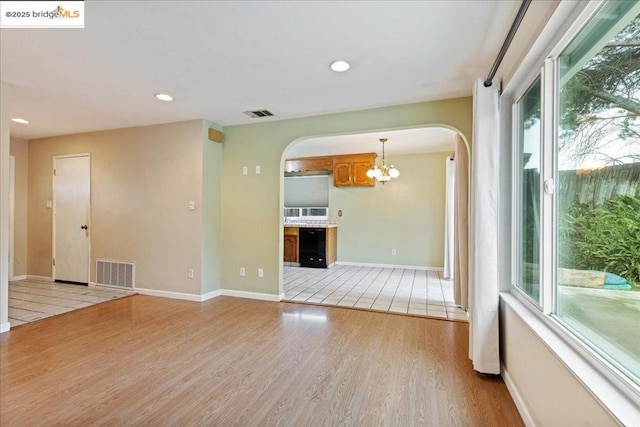 empty room featuring an inviting chandelier and light wood-type flooring