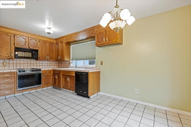 kitchen featuring pendant lighting, sink, decorative backsplash, and black appliances