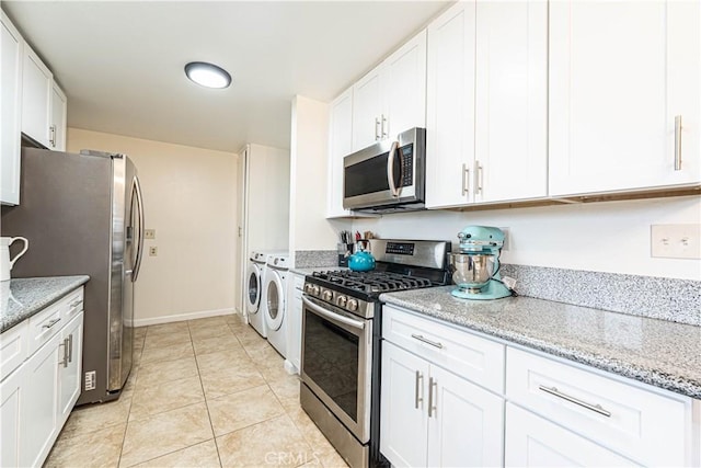 kitchen with stainless steel appliances, washer and clothes dryer, and white cabinets