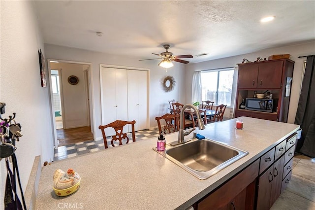 kitchen with dark brown cabinets, sink, and ceiling fan