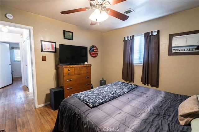 bedroom with hardwood / wood-style flooring, ceiling fan, and multiple windows