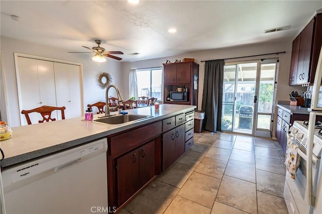 kitchen with sink, light tile patterned floors, ceiling fan, dark brown cabinets, and white appliances