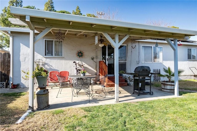 rear view of house with ceiling fan, a patio, and a lawn