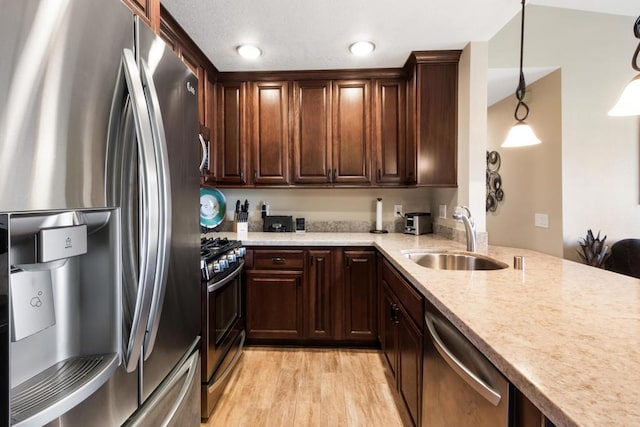 kitchen with sink, decorative light fixtures, light hardwood / wood-style flooring, appliances with stainless steel finishes, and light stone countertops