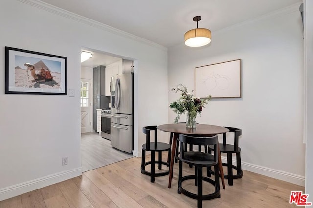 dining space with ornamental molding and light hardwood / wood-style flooring