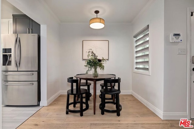 dining space featuring crown molding and light hardwood / wood-style flooring