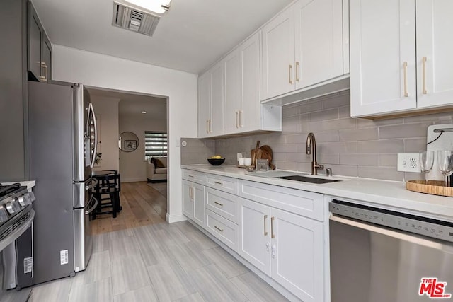 kitchen with white cabinetry, stainless steel appliances, sink, and backsplash