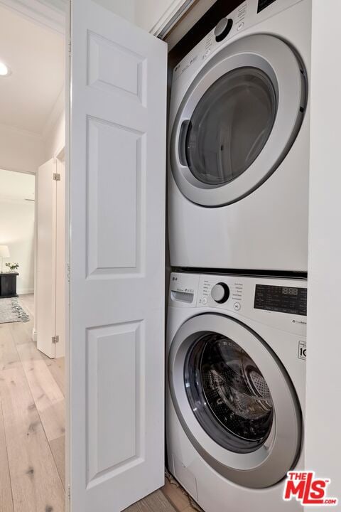 laundry room with ornamental molding, light hardwood / wood-style floors, and stacked washer / dryer