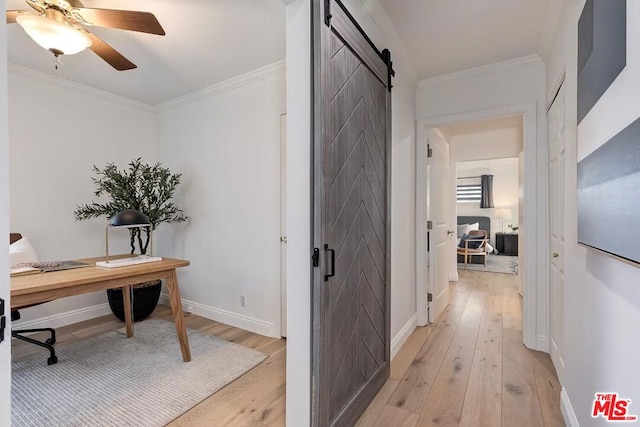 hall featuring crown molding, a barn door, and light hardwood / wood-style flooring