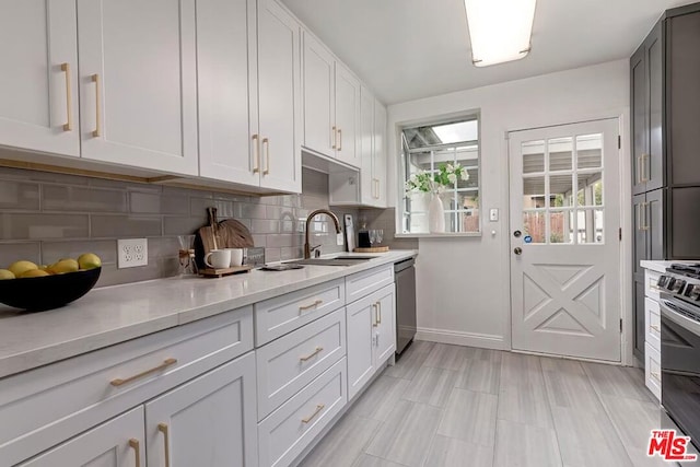 kitchen with tasteful backsplash, sink, white cabinets, light stone counters, and stainless steel appliances