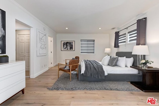 bedroom featuring ornamental molding and light hardwood / wood-style flooring