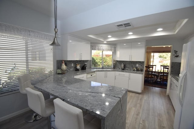 kitchen featuring white cabinetry, a raised ceiling, and hanging light fixtures