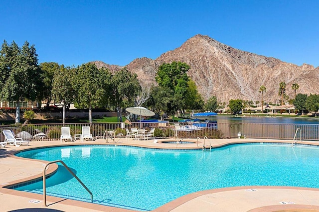 view of pool featuring a water and mountain view, a patio, and a community hot tub