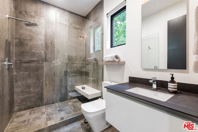 bathroom featuring vanity, tiled shower, and toilet