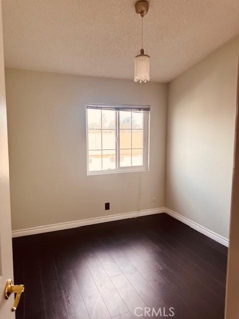 unfurnished room with dark wood-type flooring and a textured ceiling