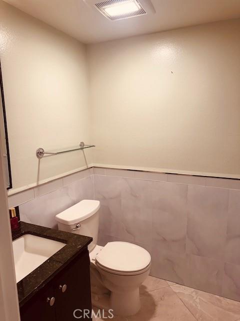 bathroom with vanity, tile walls, and toilet