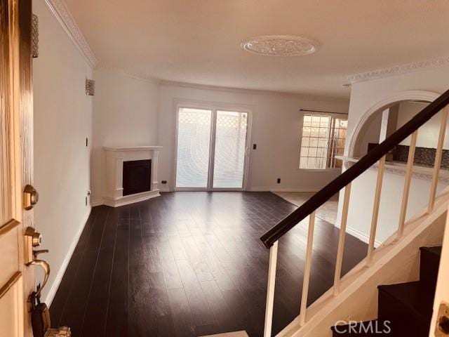 unfurnished living room with crown molding and dark wood-type flooring