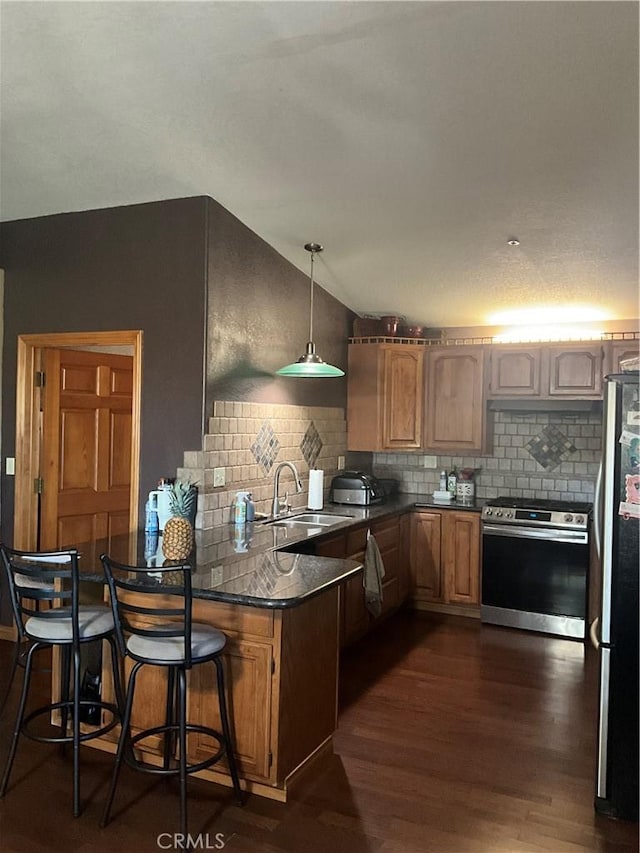 kitchen featuring a breakfast bar, sink, hanging light fixtures, appliances with stainless steel finishes, and kitchen peninsula