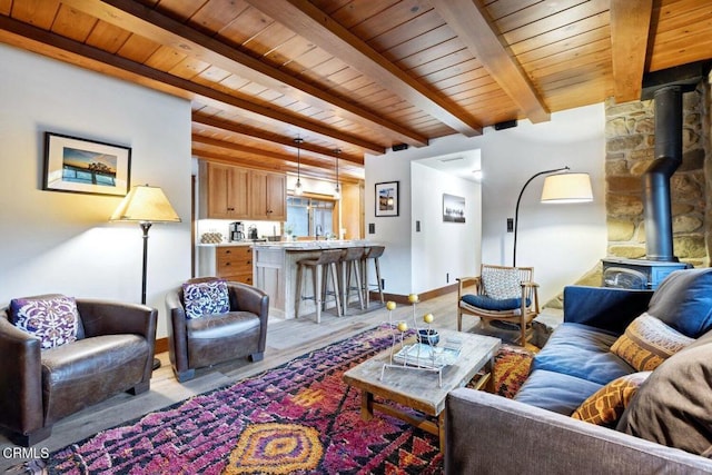 living room with beam ceiling, wood ceiling, light wood-type flooring, and a wood stove