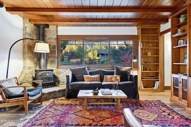 sitting room with beam ceiling, a wood stove, wood ceiling, and light hardwood / wood-style floors