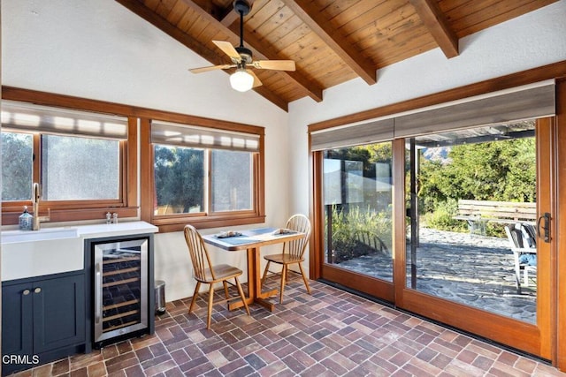 sunroom / solarium with sink, ceiling fan, vaulted ceiling with beams, wine cooler, and wooden ceiling