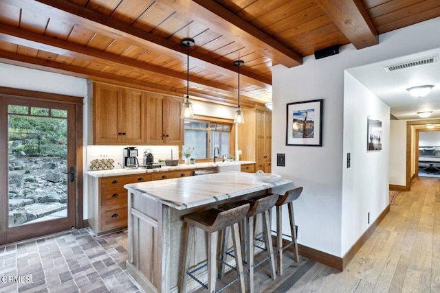 kitchen with a breakfast bar, hanging light fixtures, wooden ceiling, kitchen peninsula, and beamed ceiling