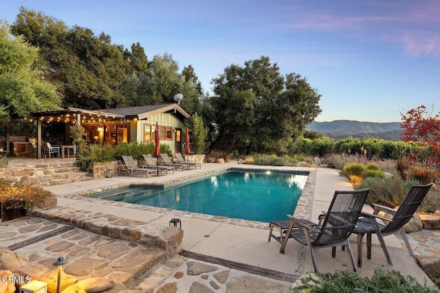 view of swimming pool featuring a mountain view, a patio area, and an outdoor structure