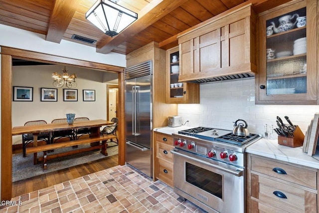 kitchen featuring hanging light fixtures, premium appliances, a notable chandelier, decorative backsplash, and beamed ceiling