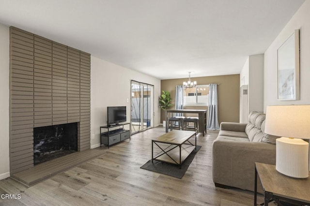 living room featuring hardwood / wood-style flooring, a fireplace, and an inviting chandelier