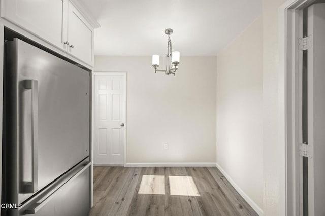 unfurnished dining area with light hardwood / wood-style floors and a chandelier