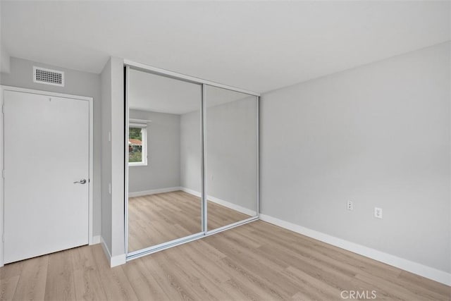 unfurnished bedroom with light hardwood / wood-style floors and a closet