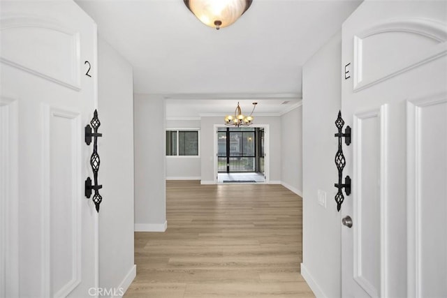 corridor with a notable chandelier and light hardwood / wood-style floors