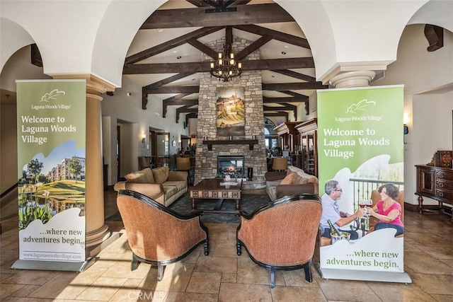 interior space featuring ornate columns, an inviting chandelier, high vaulted ceiling, a fireplace, and beam ceiling