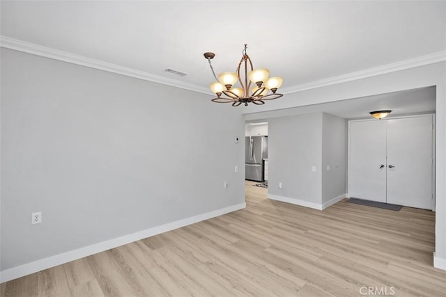 spare room featuring crown molding, light hardwood / wood-style floors, and an inviting chandelier