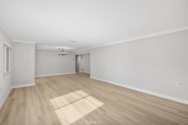 empty room featuring an inviting chandelier, crown molding, and light wood-type flooring