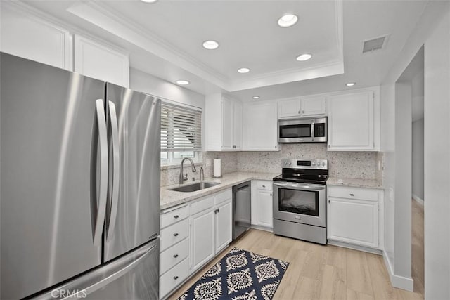 kitchen with sink, white cabinetry, appliances with stainless steel finishes, a raised ceiling, and backsplash