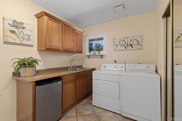 laundry area featuring washer and clothes dryer, sink, and light tile patterned floors